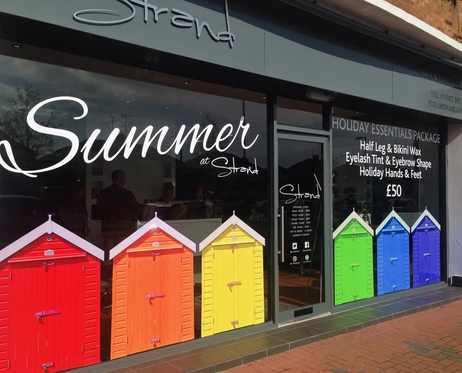 Strand Hair Salon summer window campaign with brightly coloured beach huts